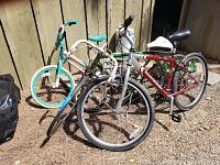 Four bicycles positioned outdoors near a wooden fence, showing all bikes in the lot.