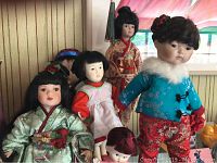 Group view of six porcelain dolls, showing various traditional and modern clothing details and facial features.