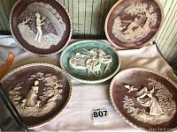 Five decorative limited edition plates by Gayle Bright Appleby displayed, showing embossed scenes of figures in nature with scalloped edges.
