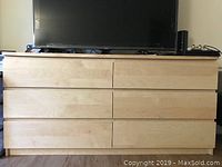 Photo of 6-drawer white stained oak veneer dresser with flat drawer fronts and integrated groove handles, showing wood grain texture and TV on top.