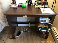 Brown wooden study table with flat top and side shelves on right side, pictured with various non-sale items on and beneath it.