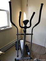 Front angle view of elliptical trainer showing dual-action handlebars, digital monitor, and foot pedals.