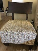 Photo of chair showing dark wood backrest and patterned cushioned seat on wooden legs.