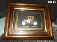 Full view of the framed artwork with wooden frame and gold trim showing the car collage and embedded watch
