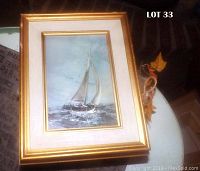 Frontal view of textured framed print of sailboat Liger One, showing gold frame and ocean scene with sailboat under cloudy sky.