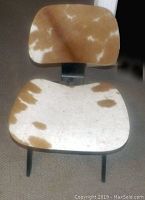 Front view of one chair showing pony-hair seat and back on black plywood frame