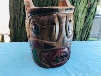 Front angle view of the carved wooden mask showing details of carving and paint