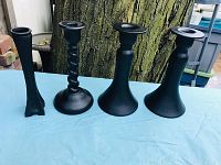 Four black satin glass candle holders on a blue cloth with tree trunk background showing different designs and sizes