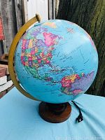 Full view of the illuminated globe showing colorful map and semi-meridian holder on wooden base