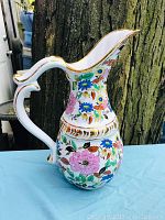 Front view of vintage Schmidt Bavaria pitcher with multicolor floral pattern and gold accents