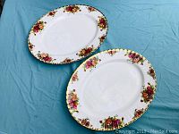 Two oval serving platters with floral patterns placed on a blue cloth, showing overall look and pattern.