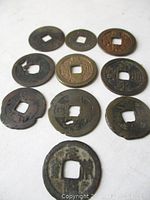 Top view of 10 Chinese cash coins laid out showing front side with inscriptions and square holes