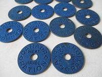 Close-up of blue circular meat ration tokens showing embossed text and central holes.