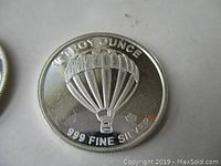 Close-up of the silver coin's hot air balloon side with weight and purity markings.