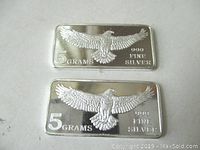 Top view showing front of two 5 gram silver ingots with detailed embossed eagle mid-flight and purity markings.