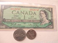 Front of 1954 Canada one dollar bill with serial number and portrait of Queen Elizabeth II, showing the two coins in front.