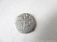 Obverse side of a small ancient Ottoman silver coin showing Ottoman script worn by age.