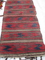 Full view of the Persian hand woven tribal rug showing the overall pattern and wear on edges.