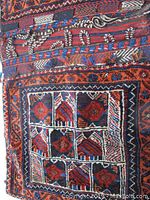 Close-up of the woven Persian tribal geometric pattern showing a detailed section of the wool carry bag with vibrant reds, blues, and browns.