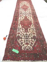 Full view of entire red and ivory patterned runner rug laid flat