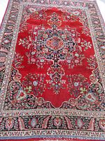 Full view of red Persian Mashad area rug laid flat