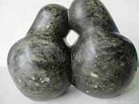 Front angled view of dark greenish-black stone carving showing two rounded birds touching beaks in a kissing pose.