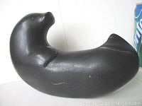 Side view of black stone seal carving showing smooth sculpted body and rounded form.