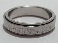 Close-up of one silver toned ring part showing engraved vine motif and band design