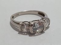 Close-up front angle of sterling silver ring with three clear crystals, showing the '925' marking on the inner band.