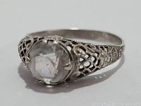 Close-up side view showing filigree pattern and clear crystal stone in sterling silver ring.