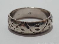 Close-up view of sterling silver band ring showing carved pattern and 925 marking inside the band.