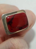 Close-up photo showing the rectangular red coral stone set in a sterling silver bezel on the ring.