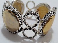 Front angled close-up of bracelet showing large gold-toned hammered disk and detailed silver framing and links