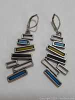 Pair of silver toned drop earrings viewed frontally showing the layout of colored rectangular bars.