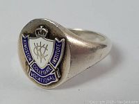 Side angled view showing the detailed enamel crest and shape of the ring