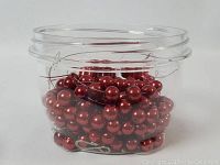 Plastic container filled with loose red beads and two red bead strands coiled inside.