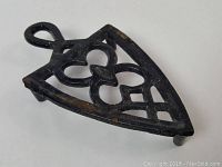 Metal iron holder with floral cutout design, shown from side angle displaying legs and handle loop