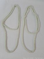 Two pearl strands arranged side by side on a white background.