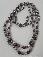 Full view of three strands of freshwater pearls in various colors spread out to show length and variety.