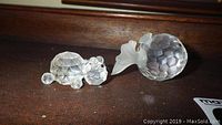 Photo showing crystal teddy bear and fish figurines on wooden surface, highlighting faceted design and detailed shapes