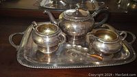 Tea set including teapot, sugar bowl, creamer on a silver plated tray.