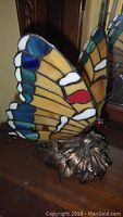 Angle showing stained glass butterfly wings and metal flower base