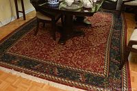 Full view of the 11x8 hand knotted area rug underneath dining table, showing general design and condition