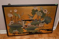 Full view of the rectangular Asian painted panel showing birds and lotus flowers on gold background in black frame with edge wear.