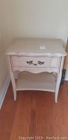 Front view of the night table showing drawer with decorative handle and shelf below
