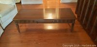 Full view of wooden coffee table placed on hardwood floor, showing rectangular top and legs.