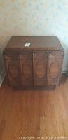 Front view of Brasilia MCM night table with oval panel doors and wood veneer finish
