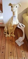 Photo showing both the large dog statue and the wooden angel statue on a wooden floor.