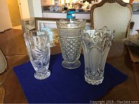 Three glass vases on dark blue cloth on table, showing entire lot.