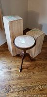 Two travertine display stands and one marble topped occasional table positioned near a corner on wooden floor.